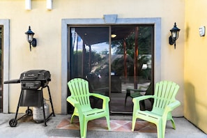 A patio area with a grill, two chairs, and a sliding glass door. - Inviting Home with Colorful Decor and Private Backyard Oasis with a Swimming Pool & Shaded Terrace (Santa Cruz)
