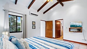 A bedroom with a bed, a TV, and a door leading to another room. - Inviting Home with Colorful Decor and Private Backyard Oasis with a Swimming Pool & Shaded Terrace (Santa Cruz)