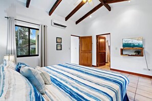 A bedroom with a bed, a TV, and a door leading to another room.