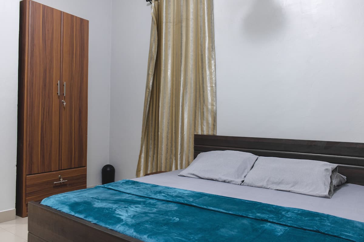 Une chambre à coucher avec un lit, une armoire en bois et un rideau.