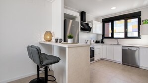 A modern kitchen with white cabinets, a stainless steel refrigerator, a built-in oven, and a dishwasher.