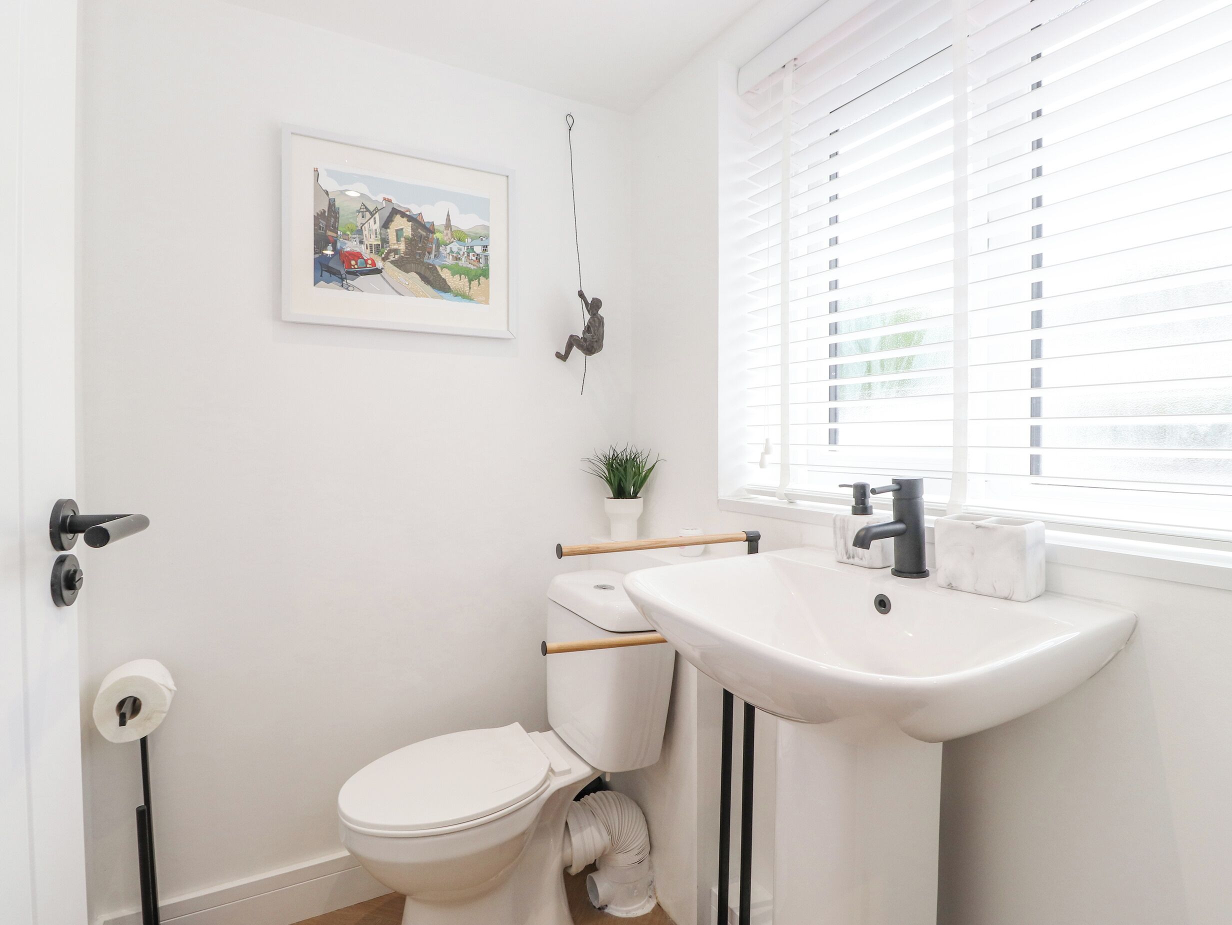 Un baño moderno con inodoro, lavamanos y ventana con persianas.