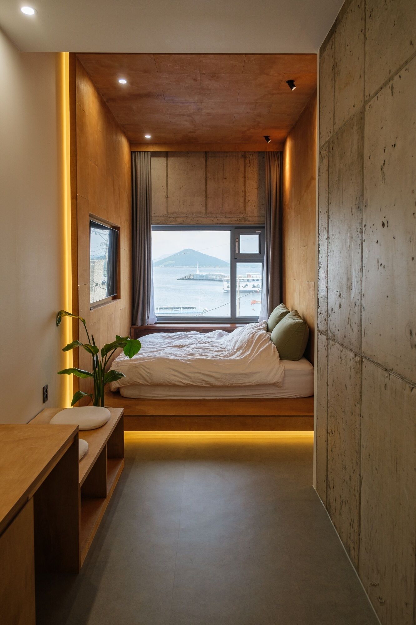 Ein Schlafzimmer mit Bett, Nachttisch und Fenster mit Meerblick.