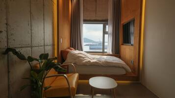 A small, cozy room with a bed, a small table, and a potted plant.