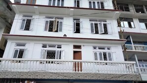 Un edificio de varios pisos con balcones, una tienda a nivel de calle y un edificio adyacente en construcción.