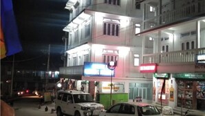 Un edificio de varios pisos con un espacio comercial en la planta baja, que incluye un letrero visible de un hotel y otros negocios.
