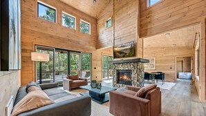 A spacious living area with a fireplace, large windows, and a high ceiling. - Starlight Ridge - Indoor pool & theater room (Smoky Mountains)