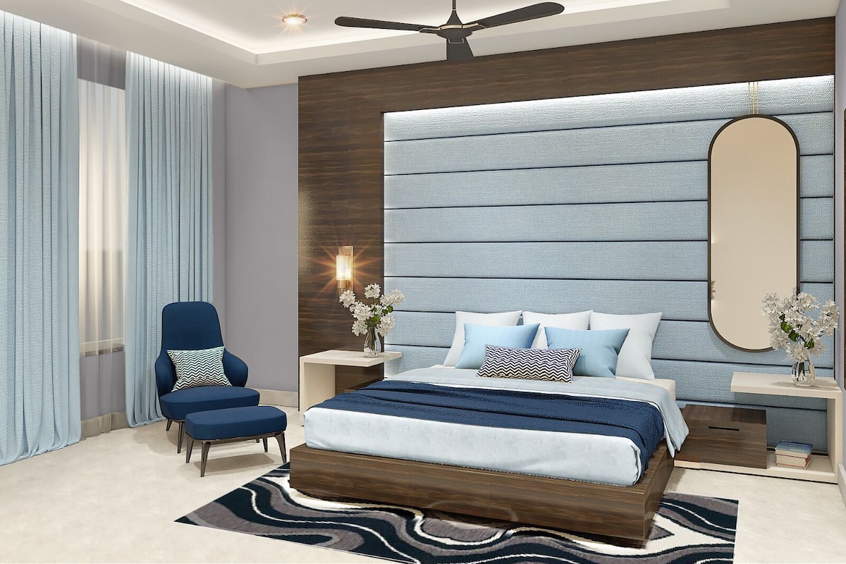 Un dormitorio moderno con una cama grande, un ventilador de techo, una mesita de noche con lámpara y una silla.