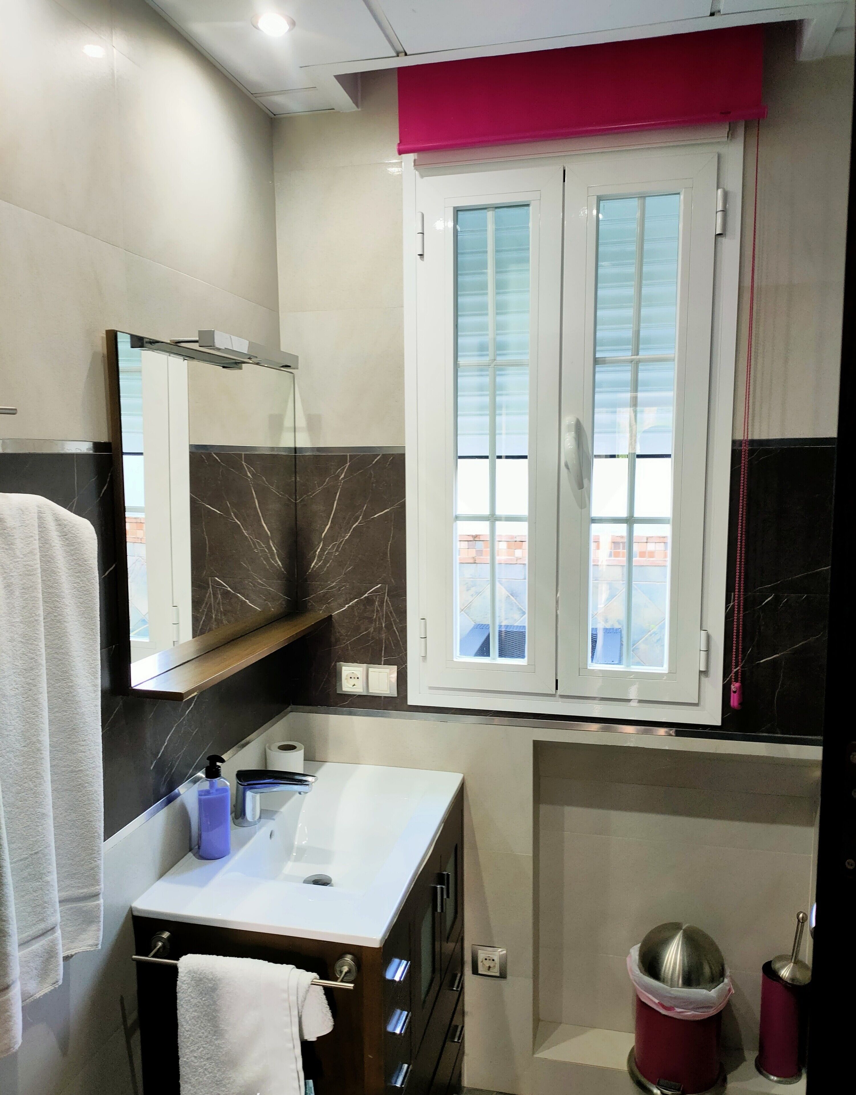 A bathroom with a vanity, mirror, and window.