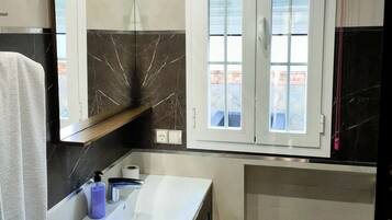 A bathroom with a vanity, mirror, and window.