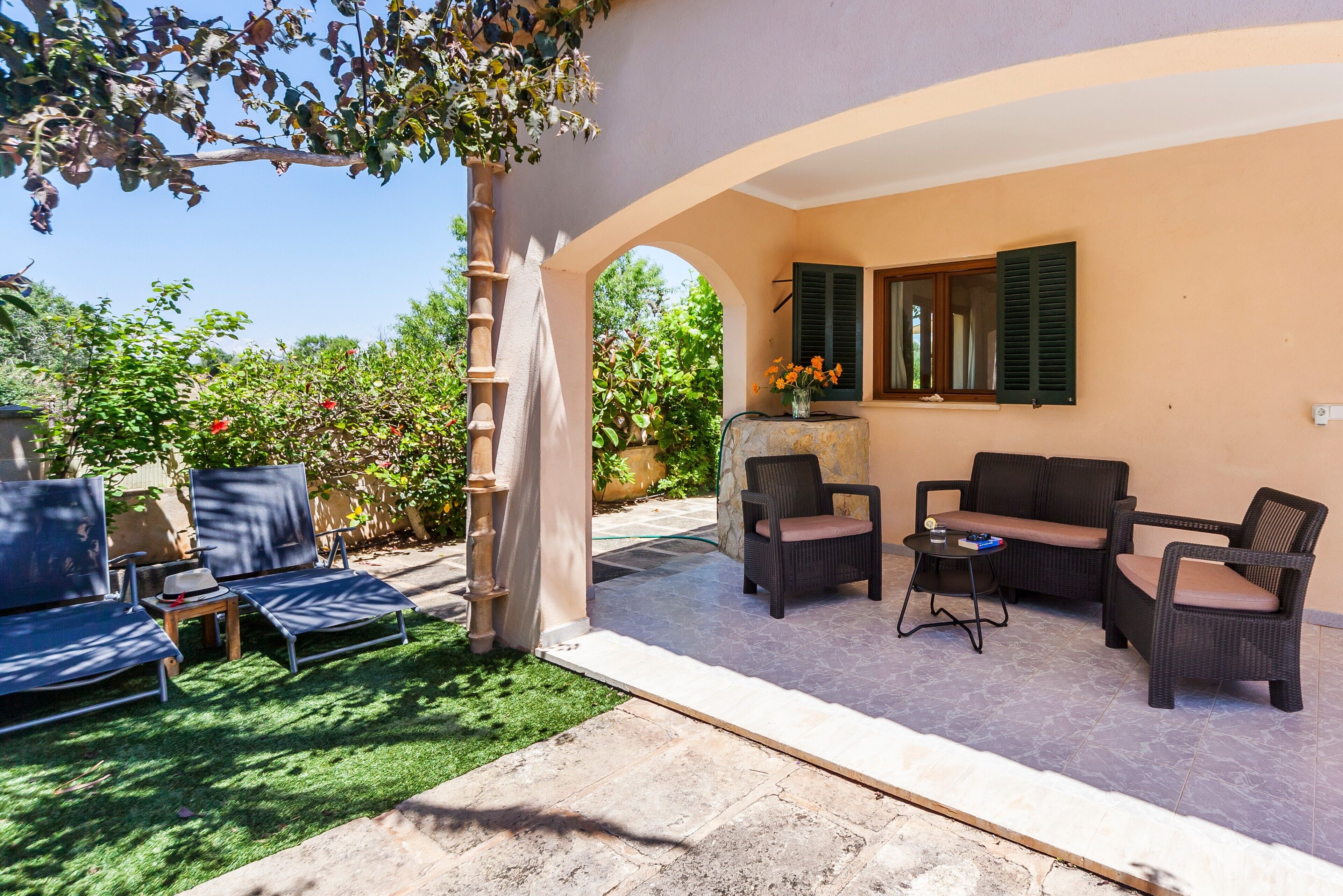 An outdoor patio area with seating, a pergola, and a view of the garden.