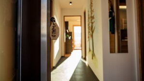 A hallway with a door labeled 'Wald' and a view into a room with a plant and a window. - Holiday Apartment "Kieserhof Wald" with Mountain View, Private Terrace & Wi-Fi (Terenten)