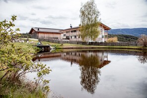 A lakeside hotel with a wooden exterior, a dining area, and a view of the lake and mountains.