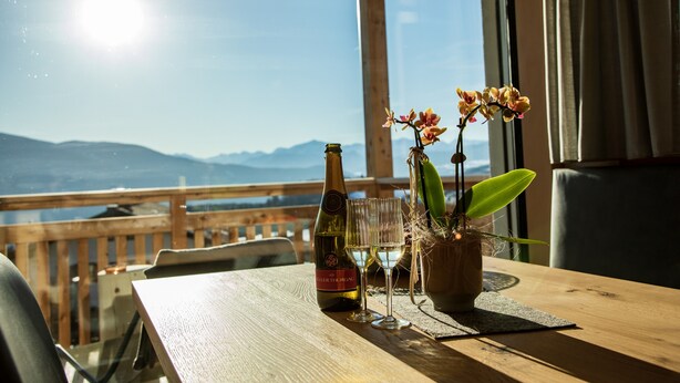 A table with a bottle, two glasses, and a potted plant. - Holiday Apartment "Kieserhof Wald" with Mountain View, Private Terrace & Wi-Fi (Terenten)