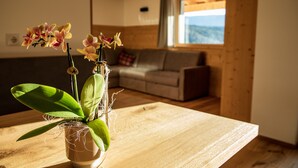 A wooden table with a potted orchid plant, a sofa, and a window with a view.