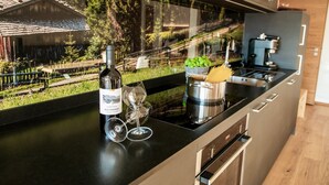 A modern kitchen with a large window, a wine bottle, two wine glasses, and a pot on the counter.