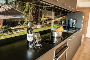 Una cocina moderna con un ventanal grande, una botella de vino, dos copas de vino y una olla sobre la encimera.