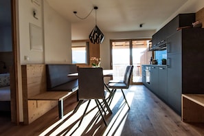 Une cuisine moderne avec un plancher en bois, un coin repas avec un banc et une vue par la fenêtre.