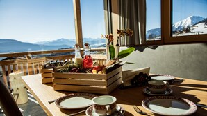 A wooden table set for breakfast with plates, cups, and a fruit basket. - Apartment "Kieserhof Berg" with Mountain View, Private Terrace & Wi-Fi (Terenten)