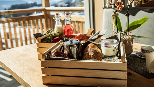 A wooden table with a tray containing bread, a coffee pot, and a potted orchid. - Apartment "Kieserhof Berg" with Mountain View, Private Terrace & Wi-Fi (Terenten)