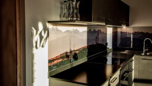 A modern kitchen with a mountain landscape mural, stainless steel appliances, and a dark wooden cabinet. - Apartment "Kieserhof Berg" with Mountain View, Private Terrace & Wi-Fi (Terenten)