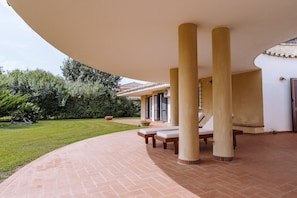 Un patio couvert doté d’un toit incurvé, de colonnes et de sièges d’extérieur.
