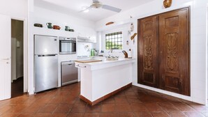 A kitchen with a refrigerator, oven, and dishwasher. There is a wooden door with a window and a ceiling fan. - Holiday Home 'Villa Degli Olivi' with Sea View, Garden, Terrace & Wi-Fi (Pula)