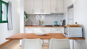 A compact kitchen with white cabinets, a wooden table, and a white refrigerator.