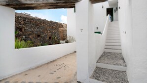 A white-walled corridor with a stone wall and a staircase leading to a door.