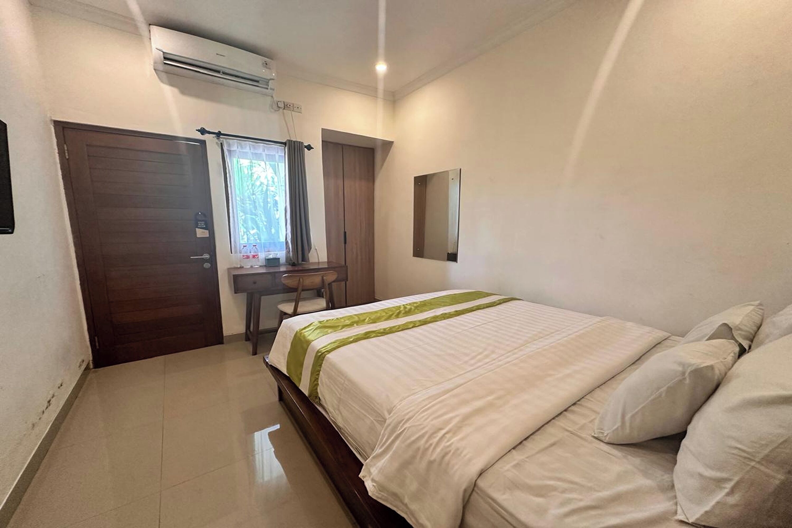 A bedroom with a bed, a desk, and a window with curtains.