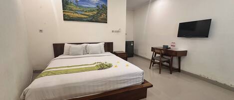 A bedroom with a bed, a desk, a TV, and a painting on the wall.