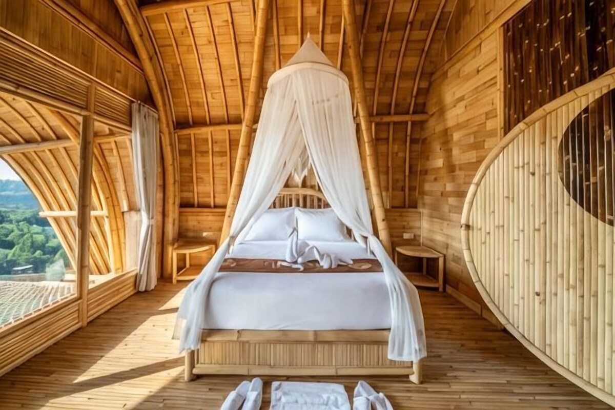 A room with a canopy bed, wooden walls, and a view of the outdoors.