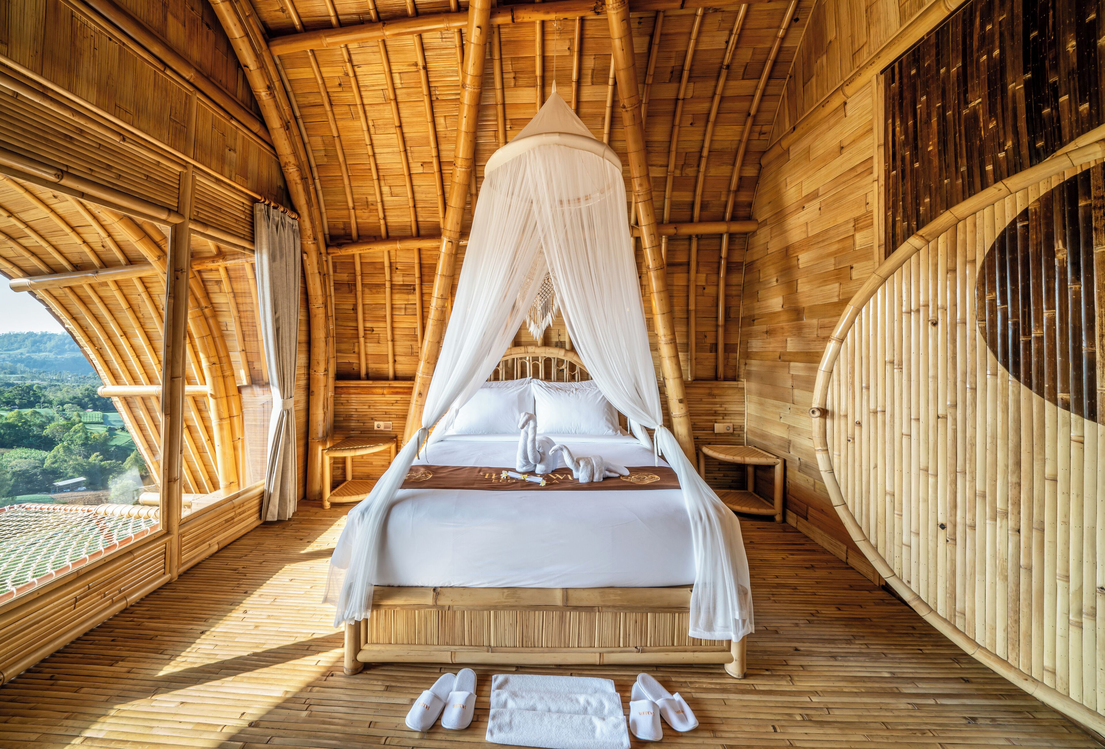 A room with a bed under a canopy, wooden walls, and a view of the landscape.