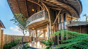 A building with a curved roof structure and a balcony. - The Dewi Eco Bamboo Villa (Kintamani)