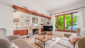 A modern living room with a fireplace, sofa, television, and large windows. - Apartment 'Casa Faro' with Sea View, Wi-Fi and Air Conditioning (Puerto Pollensa)