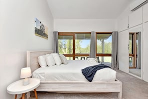 Ein modernes Schlafzimmer mit einem großen Bett, einem Nachttisch und Blick ins Freie.