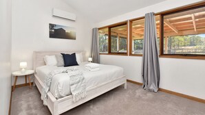 A bedroom with a bed, bedside tables, a window with curtains, a wall-mounted air conditioner, and a framed picture. - The Reserve Homestead walk to vineyards (Pokolbin)