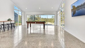 A spacious room with a pool table, a dining area with stools, and large windows offering a view of the outdoors. - The Reserve Homestead walk to vineyards (Pokolbin)