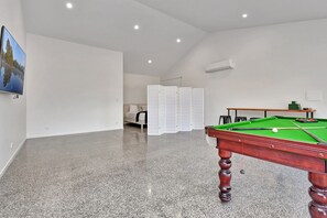A spacious room with a pool table, a sofa, and a large window.