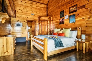 Een houten blokhut interieur met een bed, houten wanden en een kleine tafel met een lamp.