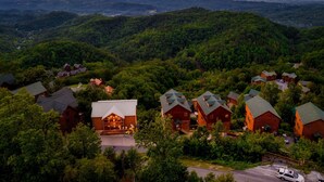 Un chalet doté de plusieurs cabanes en rondins, entouré de collines boisées et offrant une vue sur des montagnes lointaines.