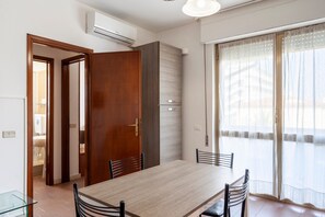 A dining area with a wooden table and chairs, a sliding glass door, and a view of the outside.