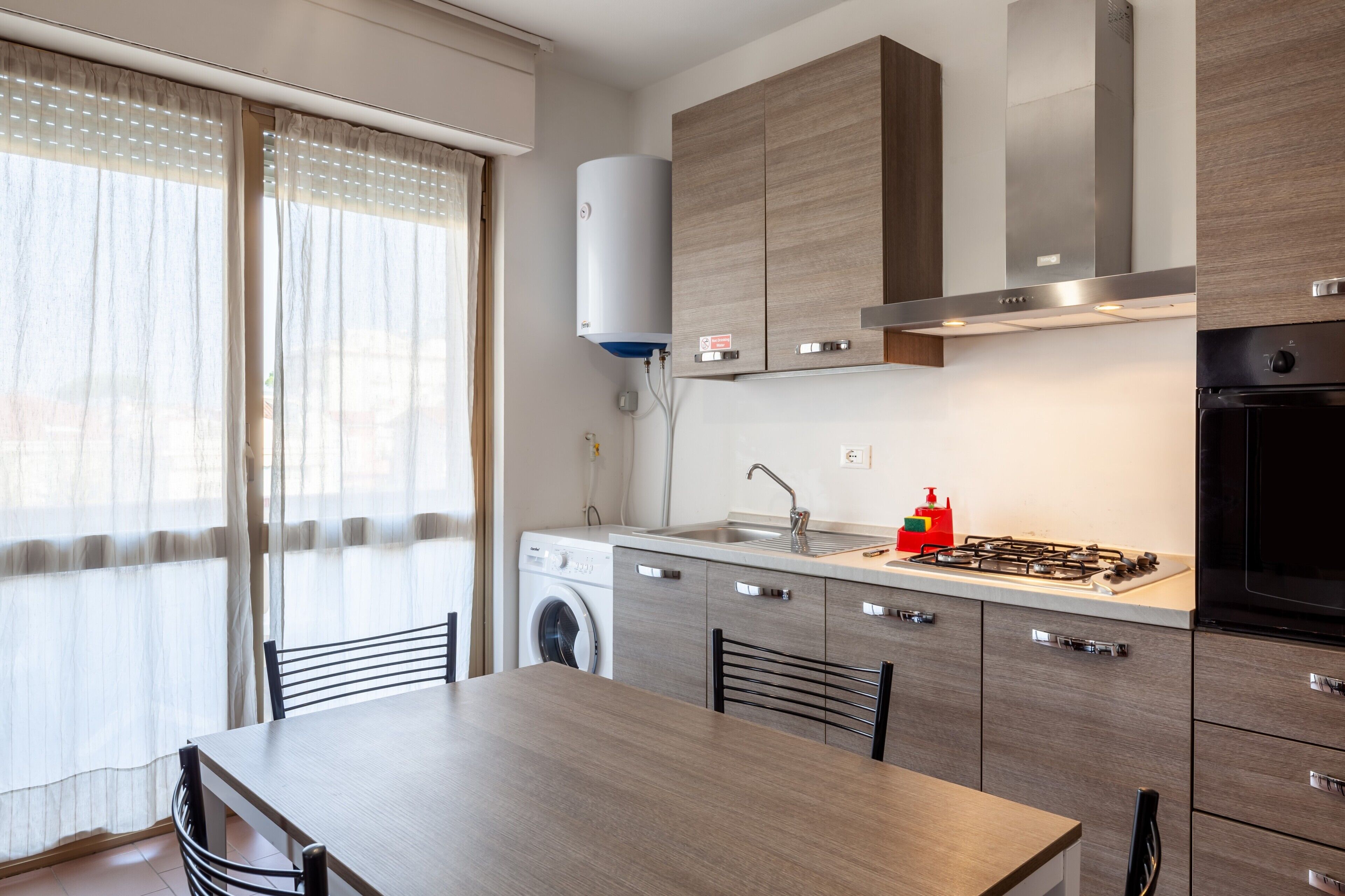 A modern kitchen with a built-in washing machine, a gas stove, and a stainless steel range hood.