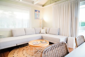 A modern living room with a sectional sofa, a round coffee table, and a wicker chair.