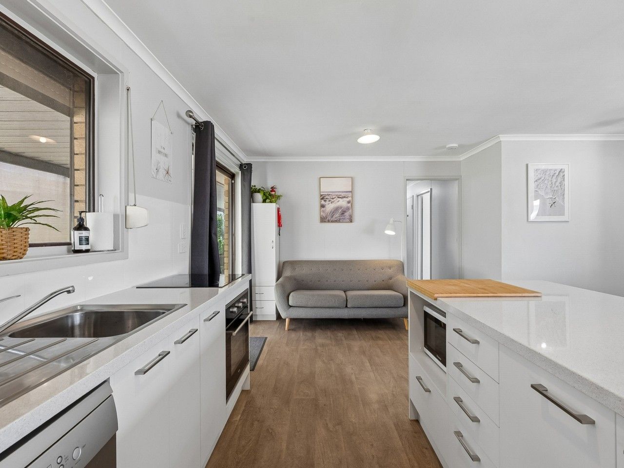 A compact kitchen with a built-in oven, a sink, and a wooden countertop.