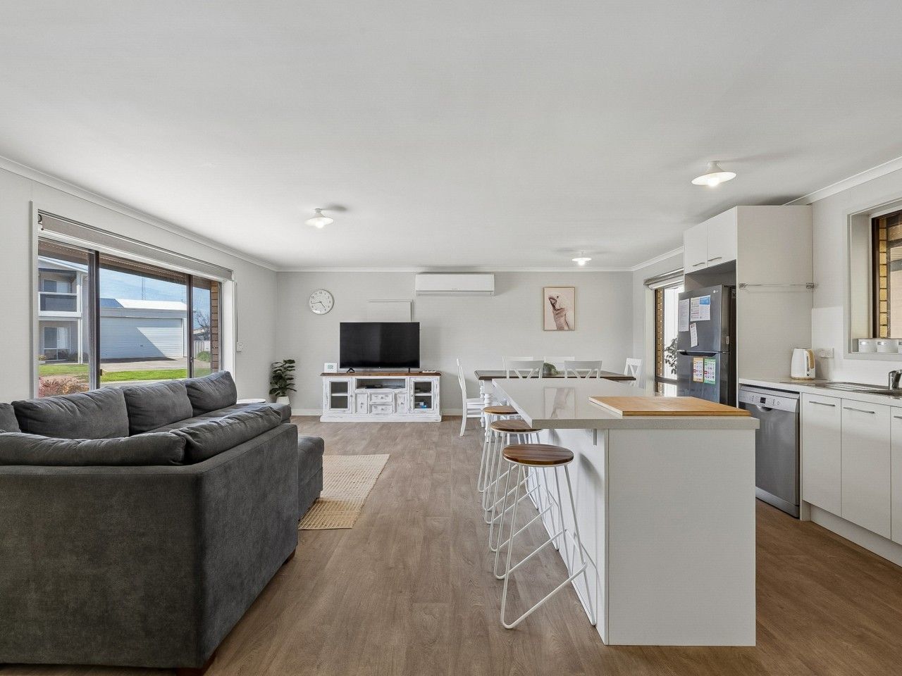 A modern living space with a grey sofa, a kitchen area, and a dining bar.