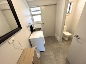 Een kleine badkamer met een wasmachine, een wastafel en een toilet.