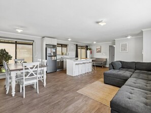A modern living space with a dining area, kitchen, and a large grey sectional sofa.