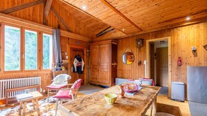 L’intérieur d’un chalet en bois comprend une table à manger, des chaises, un banc, une cheminée et un coin cuisine.