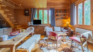 L’intérieur d’un chalet en bois comprend un coin repas, un canapé, un téléviseur et une cheminée.